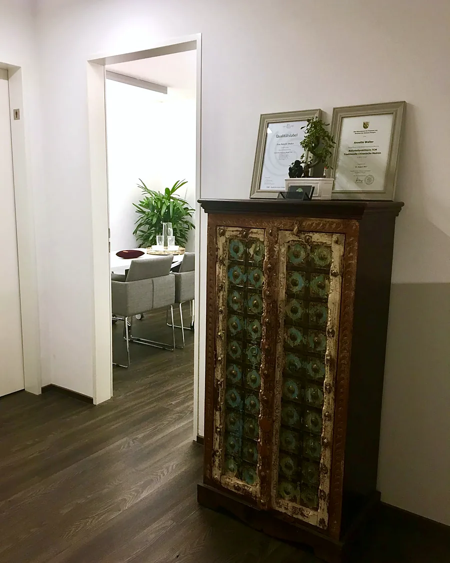 Flur der Praxis mit bemaltem Schrank und Diplomen